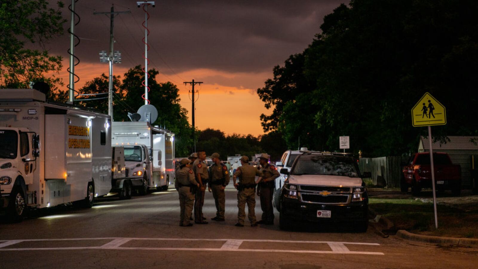 Law enforcement officers speak together outside of Robb Elementary School