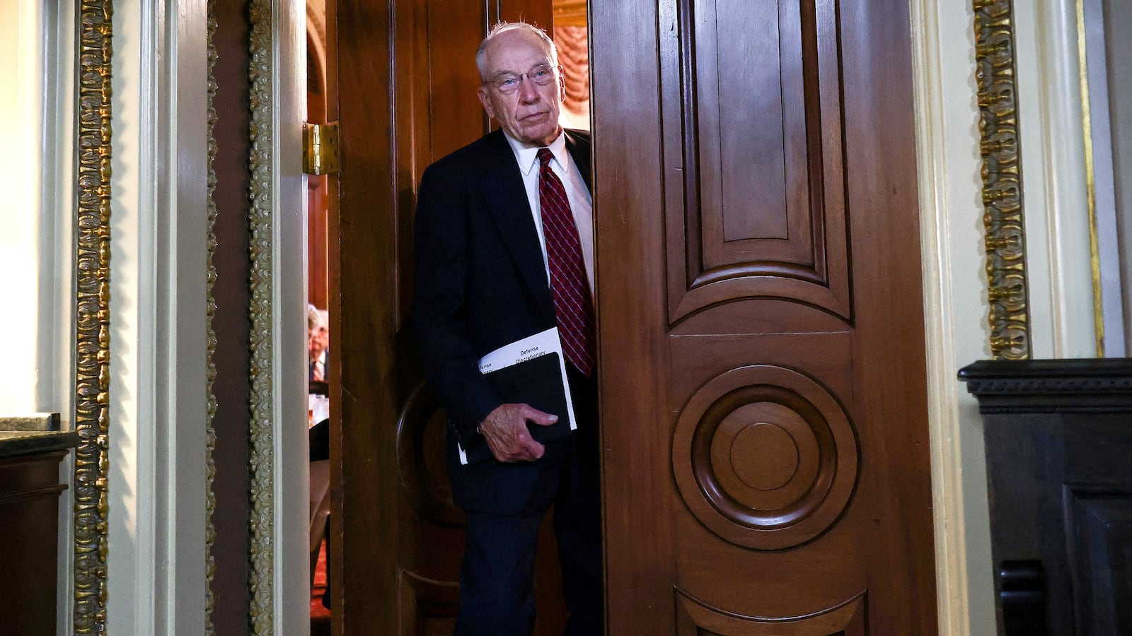 Chuck Grassley, wearing a suit and tie, walks out of a luncheon.