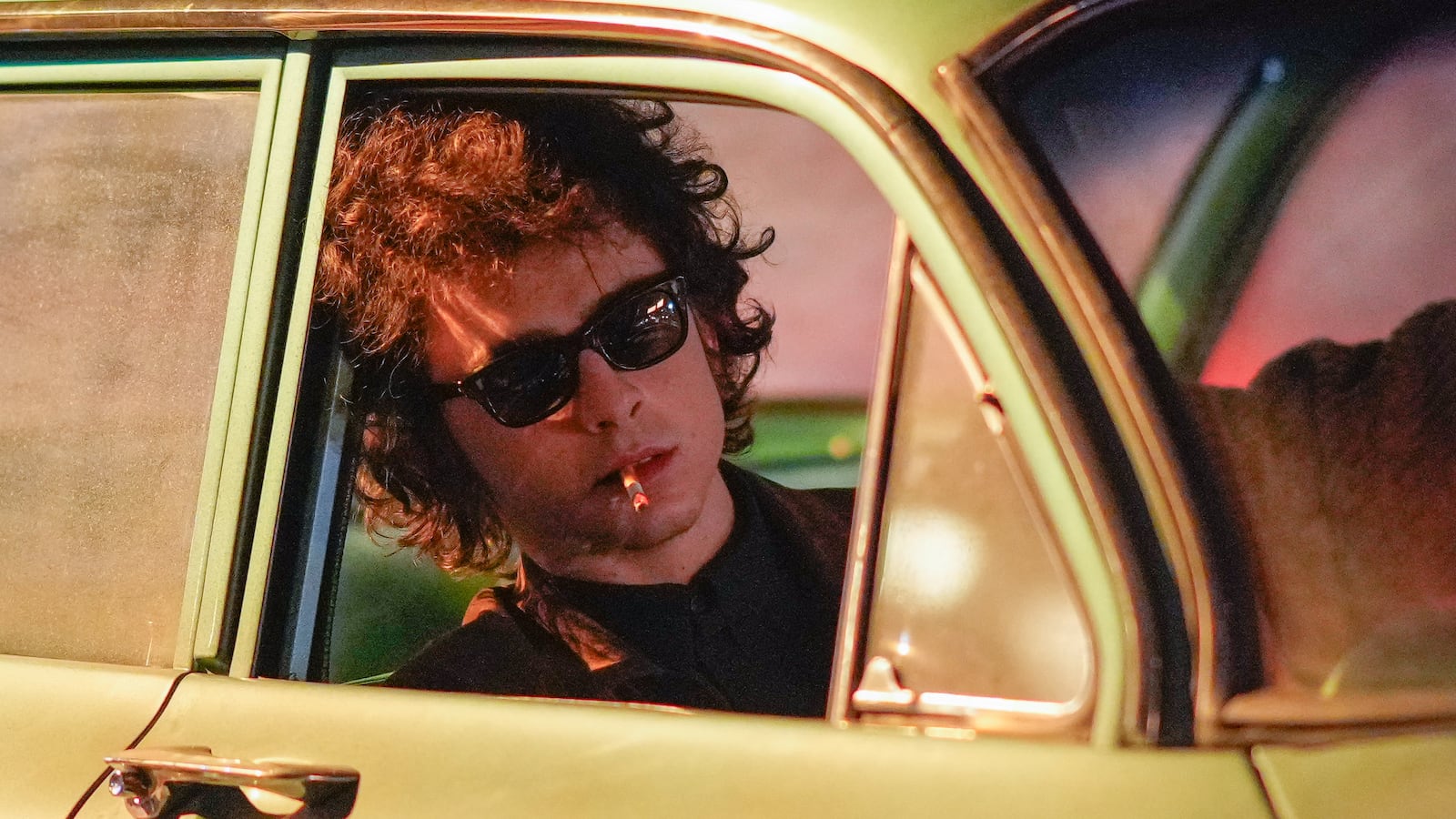 Timothee Chalamet is seen on location leaning out of a car window smoking a cigarette for the Bob Dylan biopic titled 'A Complete Unknown'