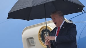 US President Donald Trump shelters from the rain under an umbrella as he disembarks from Airforce One in Los Angeles, California on March 13, 2018. (Photo by MANDEL NGAN / AFP) (Photo by MANDEL NGAN/AFP via Getty Images)