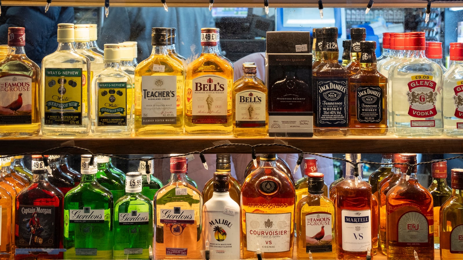 Liquor bottles lined up a store shelf.