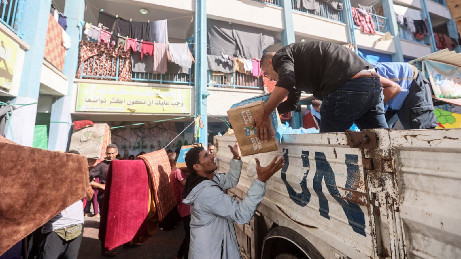 U.N. workers and volunteers unload aid from a truck at the United Nations school housing for displaced Palestinians on the 29th day of fighting between Israel and the armed Palestinian factions in Khan Younis.