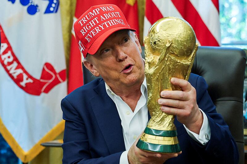 U.S. President Donald Trump wears a 'Trump Was Right About Everything!' hat while holding the FIFA World Cup Trophy, as he makes an announcement on the 2026 FIFA World Cup, in the Oval Office at the White House in Washington, D.C., U.S., August 22, 2025. REUTERS/Jonathan Ernst/File Photo