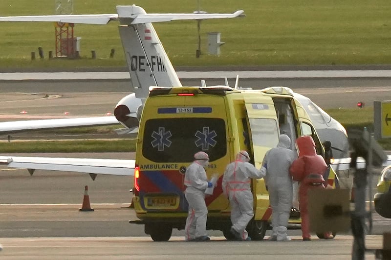 TOPSHOT - A person in a hazmat suit (2R) is escorted to a ambulance from a medical aircraft allegedly carrying some of the passengers from the cruise ship MV Hondius believed to be infected with hantavirus, at Schiphol airport near Amsterdam on May 6, 2026. A plane that left Cape Verde following the evacuation of a cruise ship hit by the hantavirus landed in Spain's Canary Islands on May 6, while a second flight headed for the Netherlands. (Photo by Lina Selg / AFP via Getty Images)