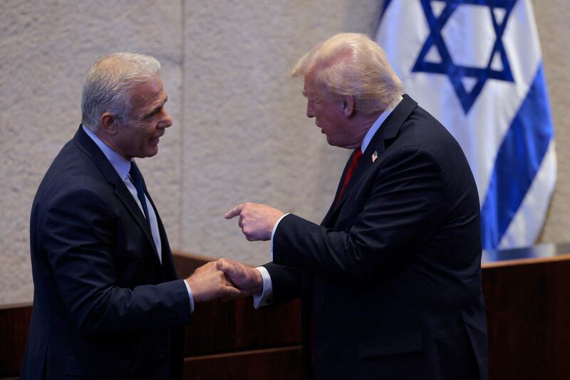 President Donald Trump (R) interacts with Israeli opposition leader Yair Lapid as he addresses the Knesset