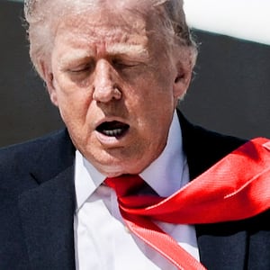 U.S. President Donald Trump's tie is blown by the wind as he walks to board Air Force One .
