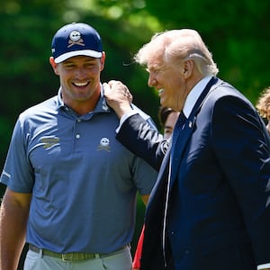President Donald Trump (R) speaks with golfer Bryson DeChambeau (C) and South African retired golfer Gary Player (L) as they watch young student athletes participate in exercise activities on the South Lawn of the White House after President Trump signed a proclamation to revive the Presidential Fitness Test Award, a competitive school-based fitness program, in Washington, DC on May 5, 2026.