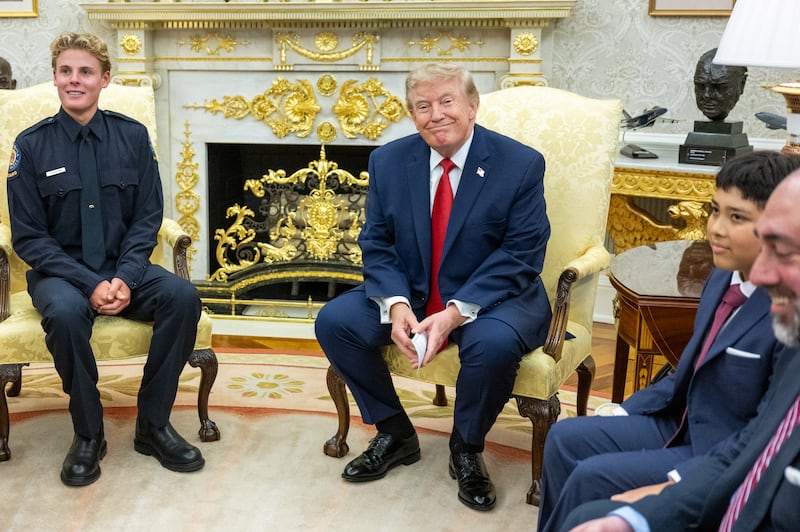 US President Donald Trump meets with lifeguard Ryder Williams (L) in the Oval Office of the White House in Washington, DC, on August 17, 2026. The 16-year-old Williams rescued 10-year-old Nathaniel Rai (pictured at R) in rough surf at Seabright Beach last month in Santa Cruz, California. (Photo by Jim WATSON / AFP via Getty Images)