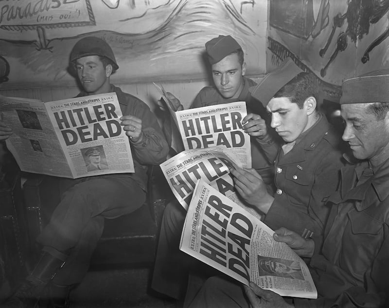 American GIs on leave in Paris reading the U.S. military newspaper Stars and Stripes, which has a headline announcing Hitler's death. The German dictator committed suicide April 30, 1945 after the collapse of the Third Reich.