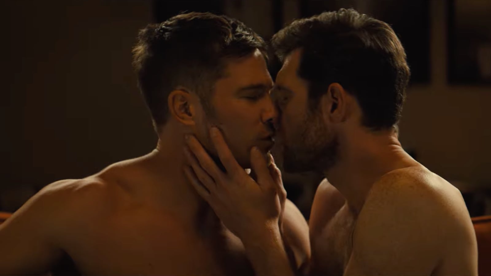 Two men kissing in a hot tub.