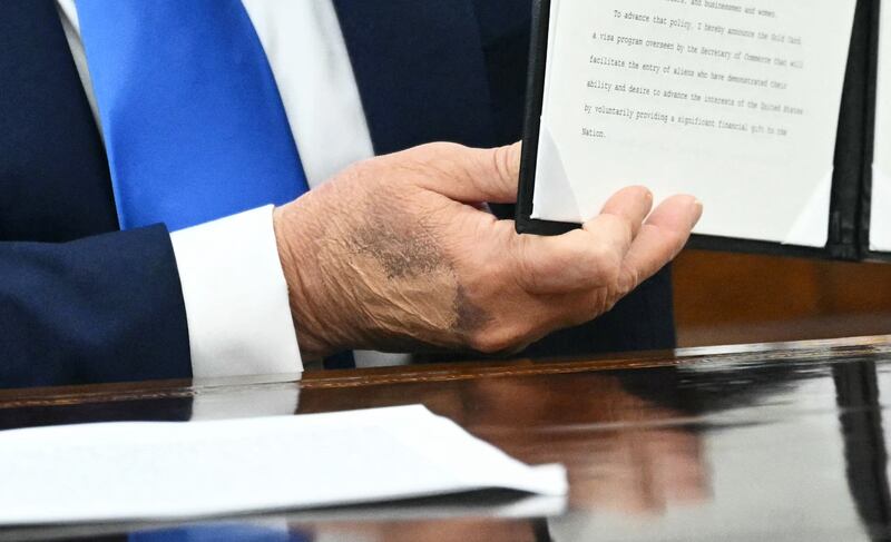 President Donald Trump displays an executive order he just signed in the Oval Office at the White House in Washington, DC, on September 19, 2025 as Commerce Secretary Howard Lutnick (L) looks on.