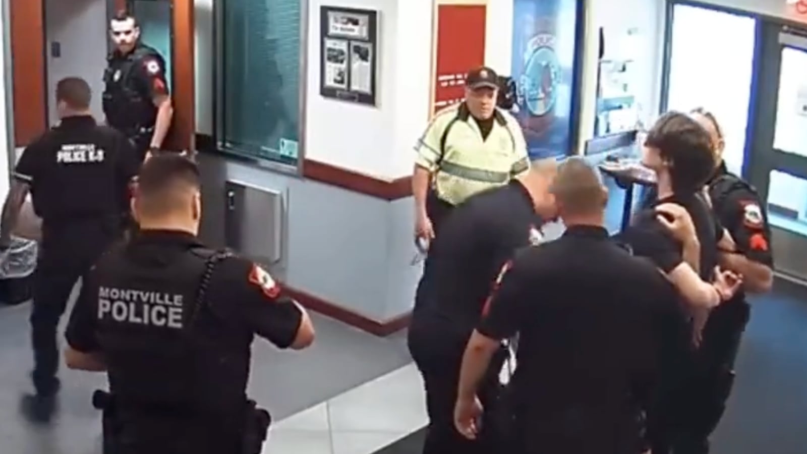 A group of officers circle a man to make an arrest in the Montville Police Department headquarters moments before a handgun went off on its own.