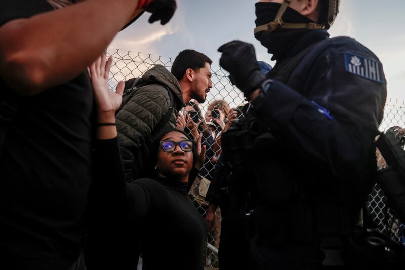 Zoe Lloyd-Trotter, 21, center, raises her hands in protest as hundreds gather to decry the arrive of Border Patrol agents