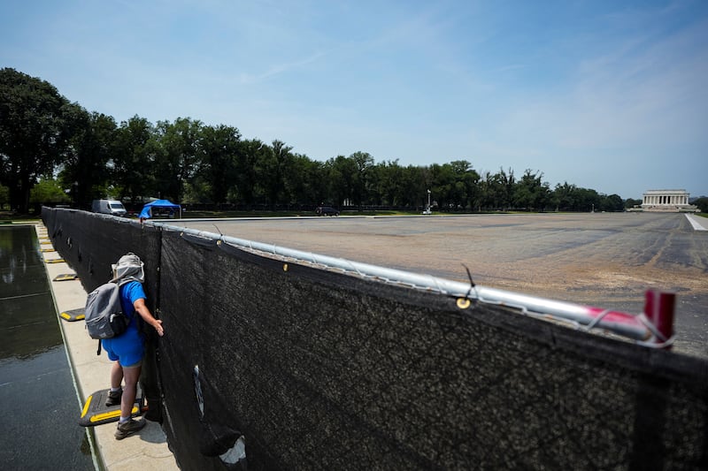 A pedestrian walks along a privacy fence to view the drained Lincoln Memorial Reflecting Pool, following renovations and Independence Day celebrations, in Washington, D.C., U.S., July 15, 2026. REUTERS/Al Drago