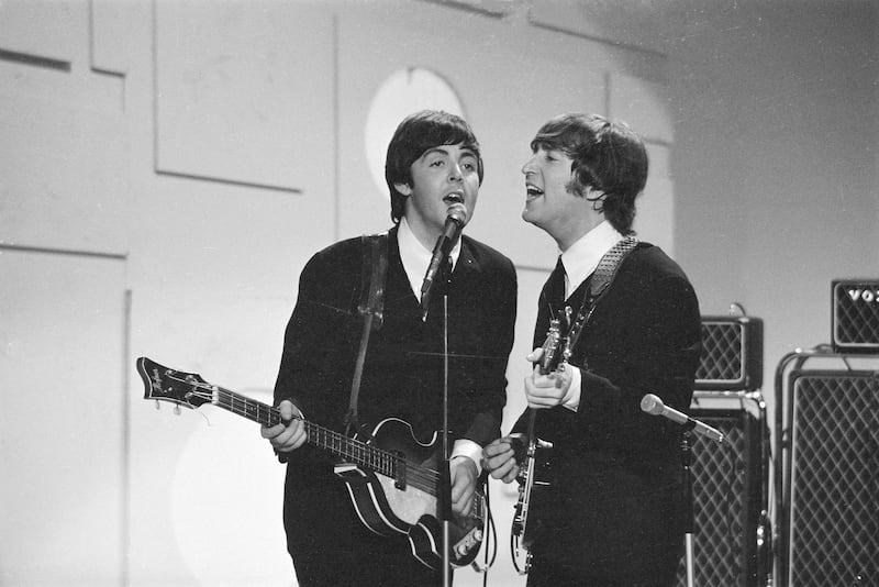 Members of the British rock band The Beatles, Paul McCartney (left) and John Lennon (1940 - 1980), sing into a microphone as they play their instruments at the taping of a segment for 'Toast of the Town,' the CBS variety program hosted by Ed Sullivan, New York, August 14, 1965. The segment aired as part of Sullivan's 19th season opener on September 12, 1965. (Photo by CBS Photo Archive/Getty Images)