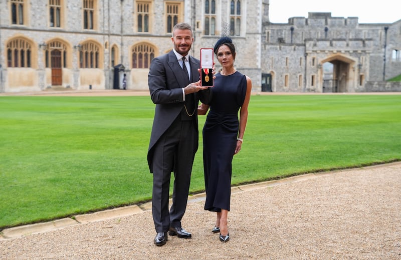 Former England footballer David Beckham (L) poses next to his wife singer and fashion designer Victoria Beckham (R) with his medal after being appointed as a Knight Bachelor (Knighthood) for services to sport and charity at an investiture ceremony at Windsor Castle on November 4, 2025. (Photo by Andrew Matthews / POOL / AFP) (Photo by ANDREW MATTHEWS/POOL/AFP via Getty Images)
