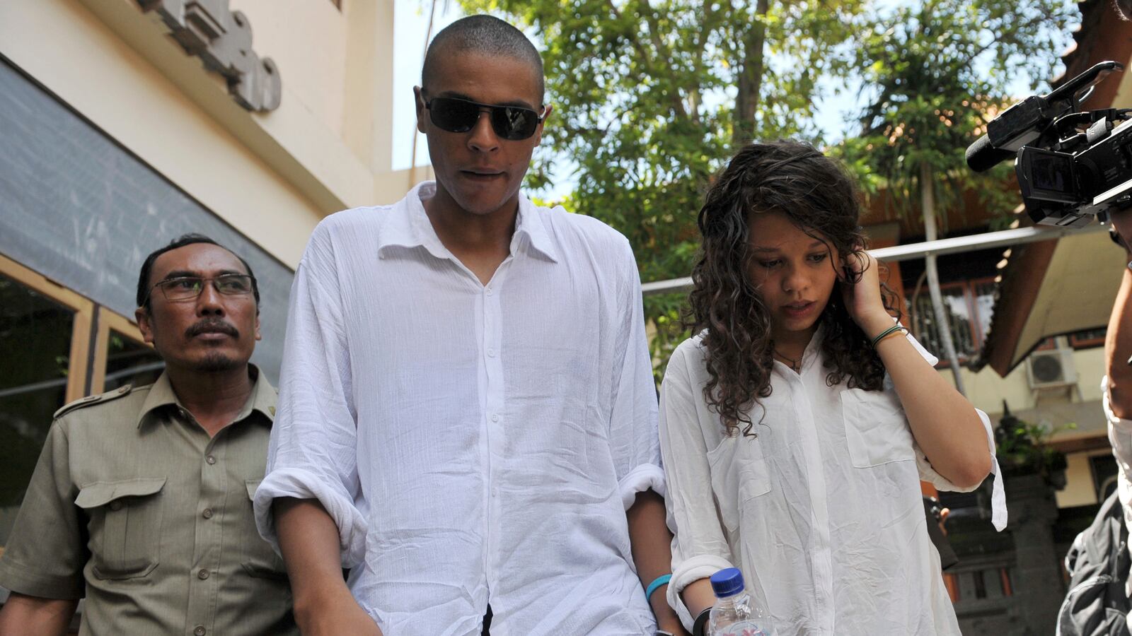 "An Indonesian plain clothes policeman escorts U.S. citizens Tommy Schaefer (C) and girlfriend Heather Mack (R), the daughter of U.S. woman Sheila von Wiese-Mack who was found dead inside a suitcase on the Indonesian holiday island of Bali.