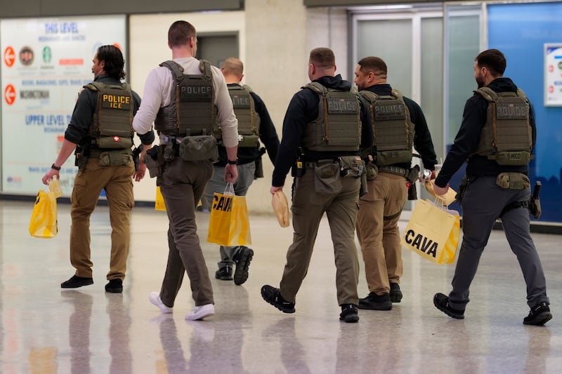 DULLES, VIRGINIA - MARCH 24: Immigration and Customs Enforcement (ICE) agents walk through Dulles International Airport with bags of CAVA on March 24, 2026 in Dulles, Virginia. The travel disruptions continue as hundreds of TSA agents quit or work without pay during a partial government shutdown. U.S. President Donald Trump deployed ICE agents to U.S. airports on Monday, with border czar Tom Homan in charge of the effort. (Photo by Heather Diehl/Getty Images)
