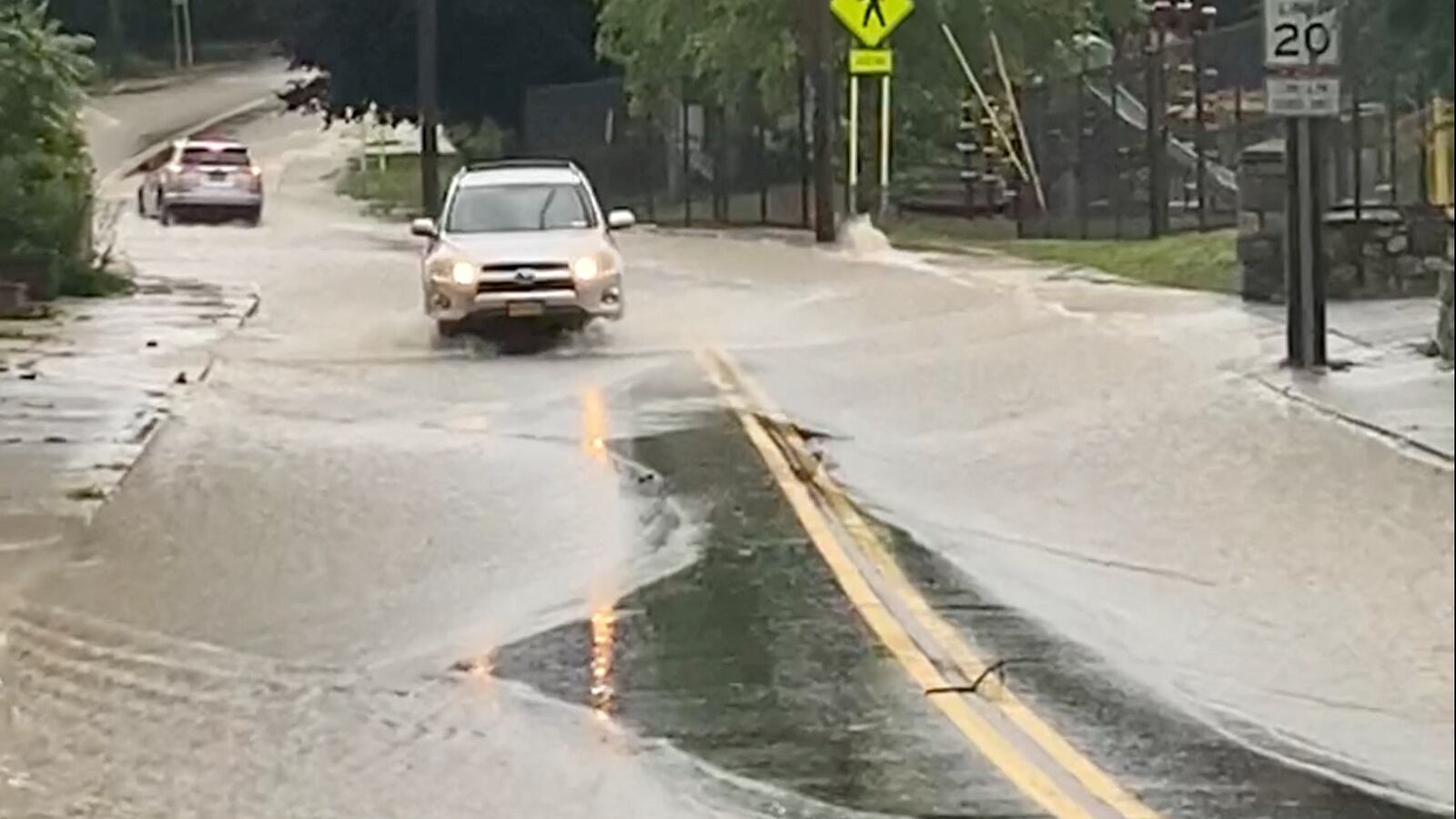 Cars drive on a flooded road in Highland Falls, New York. At least one died after apocalyptic flooding in upstate New York.