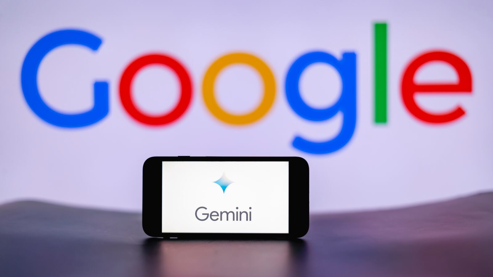 In this photo illustration, the Gemini logo is seen displayed on a mobile phone screen with Google logo in the background.