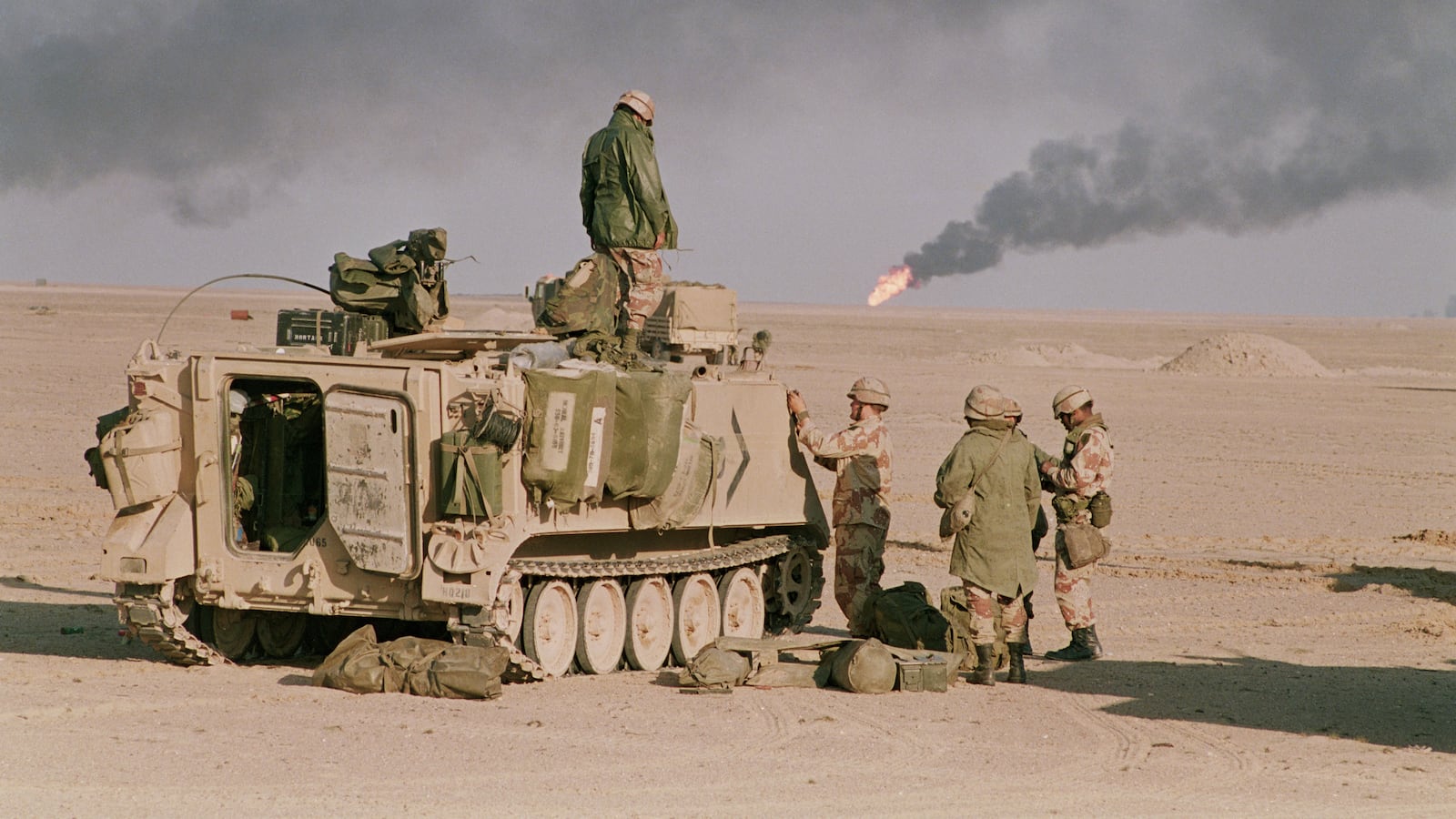 A U.S. armored personnel carrier sits in the desert at the end of the Gulf War. Oil wells burn in the background. (Photo by Peter Turnley/Corbis/VCG via Getty Images)