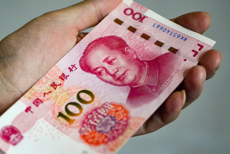 CHINA - 2026/02/14: In this photo illustration, a hand holds a 100-yuan RMB banknote at an angle, displaying both the obverse design and the security features on its edge. The Chinese yuan has experienced mild fluctuations against the US dollar in recent periods, with a general trend of moderate appreciation. (Photo Illustration by Sheldon Cooper/SOPA Images/LightRocket via Getty Images)
