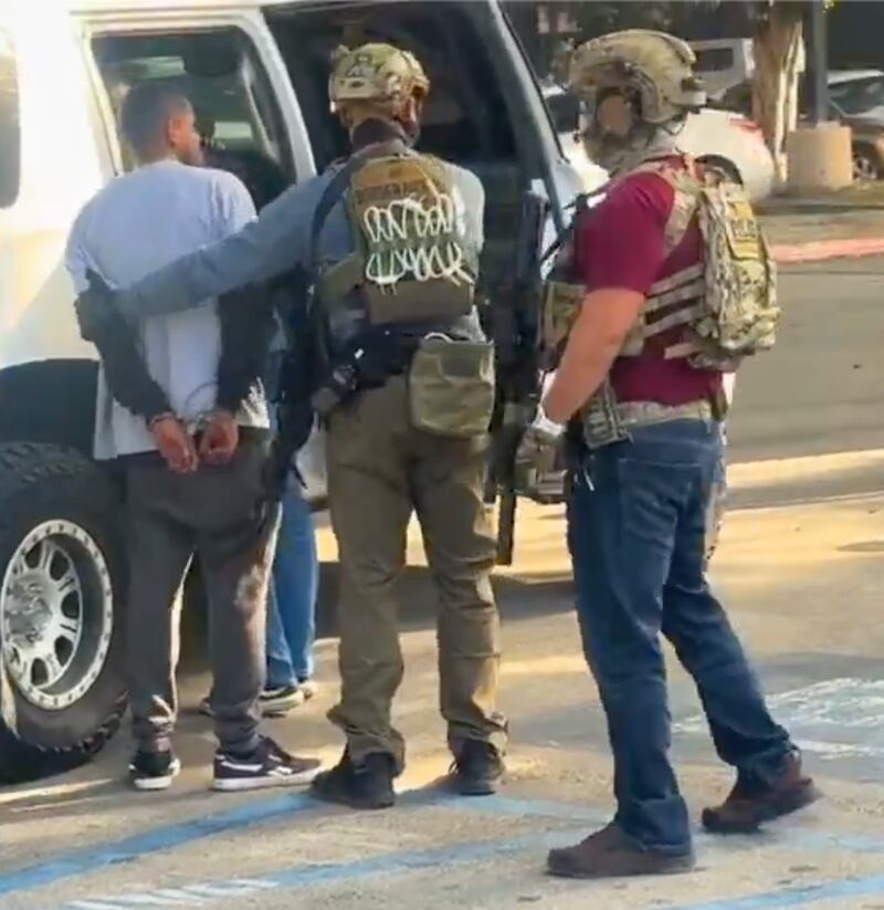The man is placed into an ICE vehicle by officers.