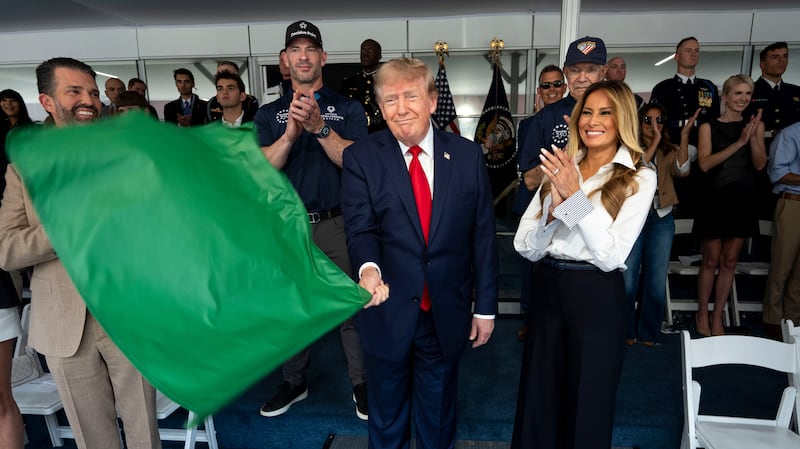 WASHINGTON, DC - AUGUST 23: U.S. President Donald Trump waves the green flag to start the race with first lady Melania Trump and Donald Trump Jr. at the NTT INDYCAR Series on August 23, 2026 in Washington, DC. U.S. President Donald Trump established the Freedom 250 Grand Prix weekend as part of the yearlong celebration of America's 250th anniversary. (Photo by Doug Mills - Pool/Getty Images)