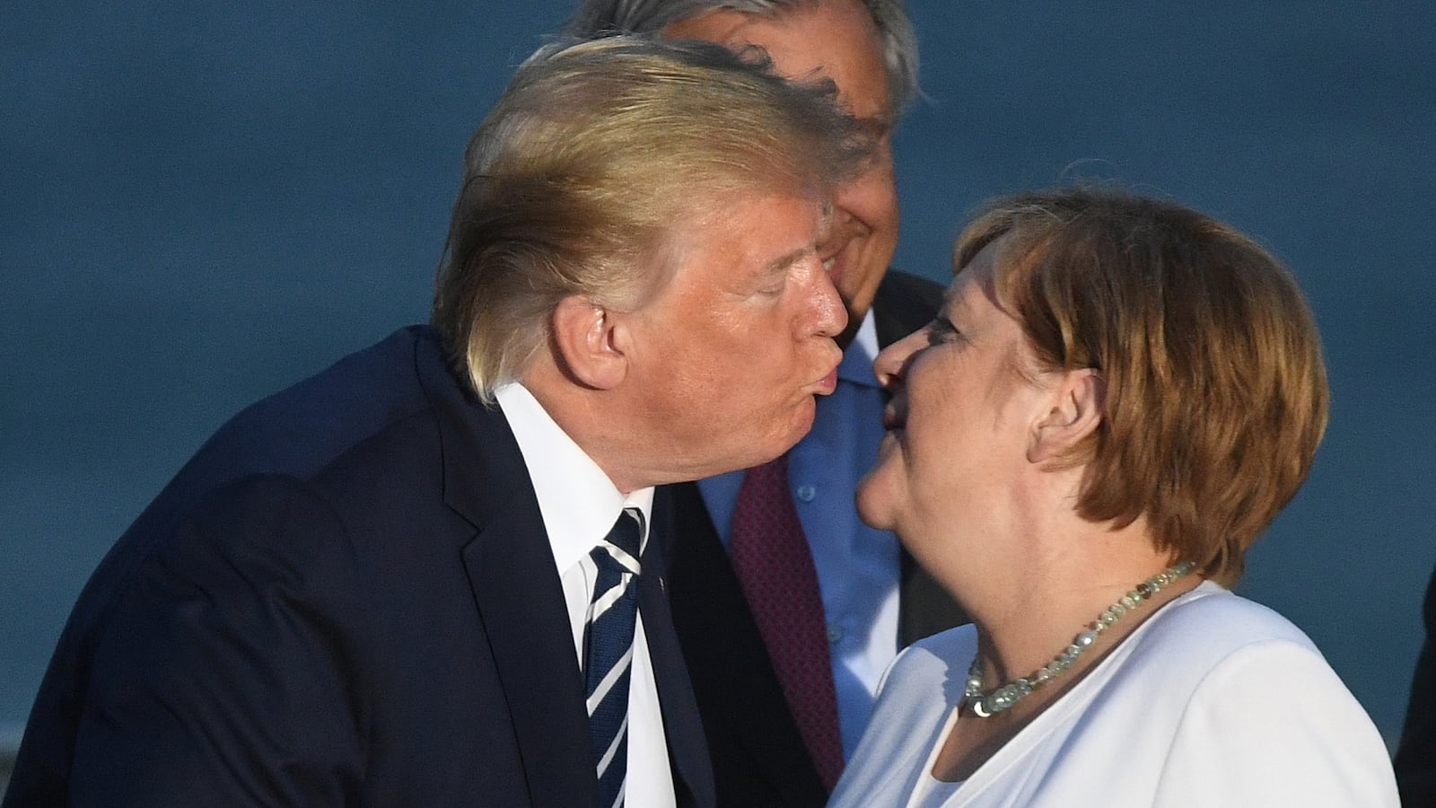 Donald Trump kisses German Chancellor Angela Merkel during a family photo opportunity at the G7 summit in Biarritz, France, Aug. 25, 2019.