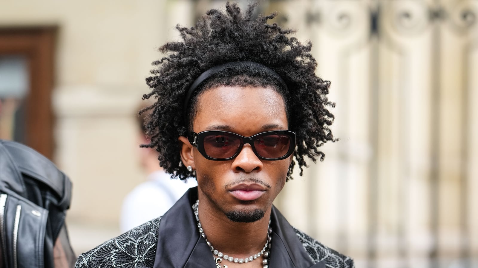 PARIS, FRANCE - JUNE 26: d4vd wears black Chanel sunglasses, diamond stud earrings, white gold diamond choker, silver Chrome hearts necklace, black silver floral beaded oversized Amiri blazer jacket, outside Amiri, during the Paris Fashion week Men's Spring/Summer 2026 on June 26, 2025 in Paris, Franco (Photo by Edward Berthelot/Getty Images)
