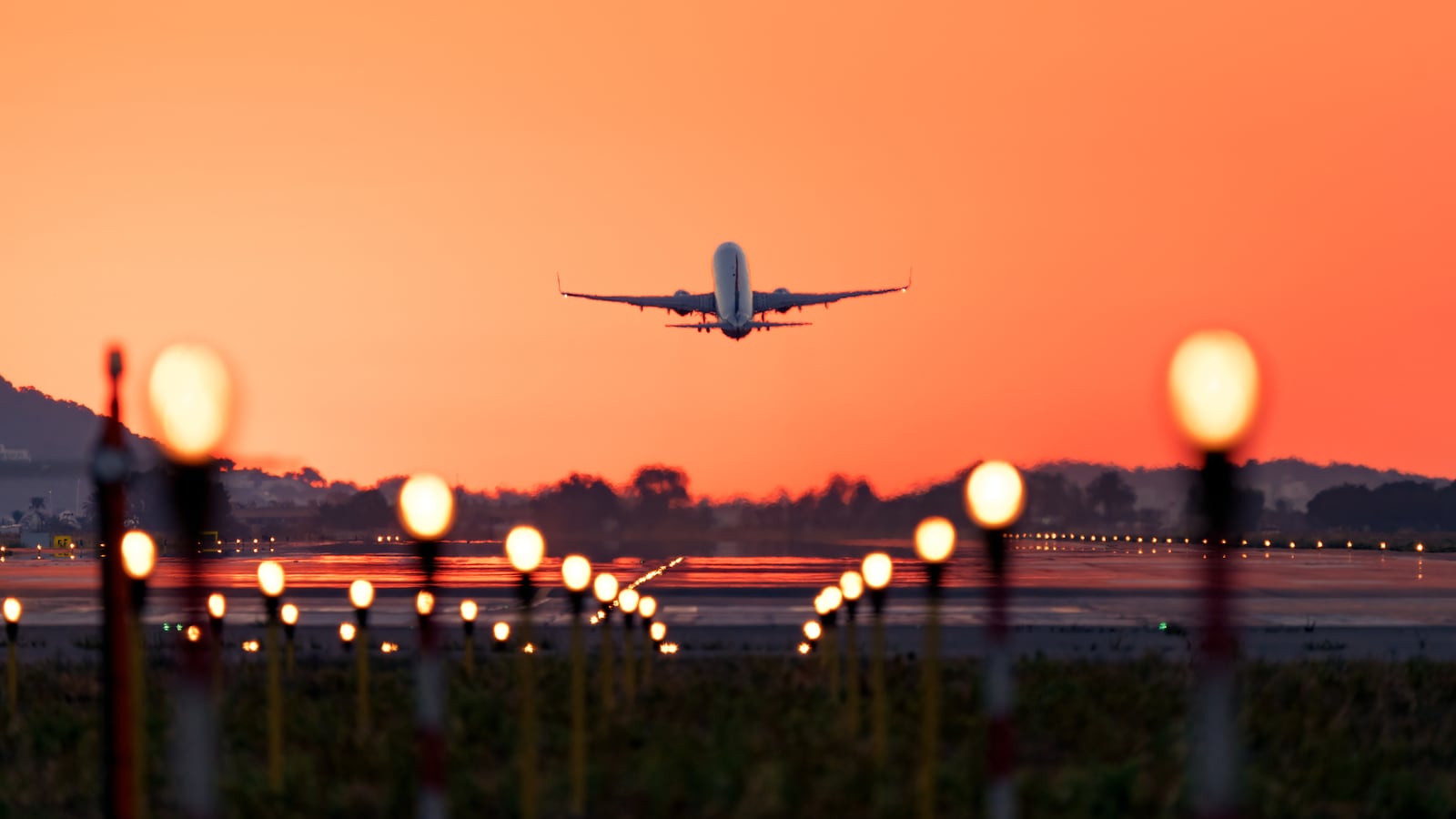 Stock image of an airplane taking off at sunrise.