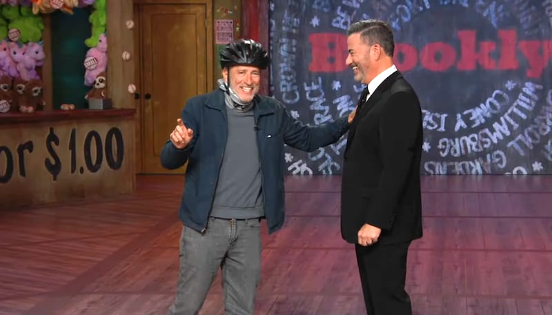 The Daily Show, Jon Stewart with a helmet laughing with Jimmy Kimmel.