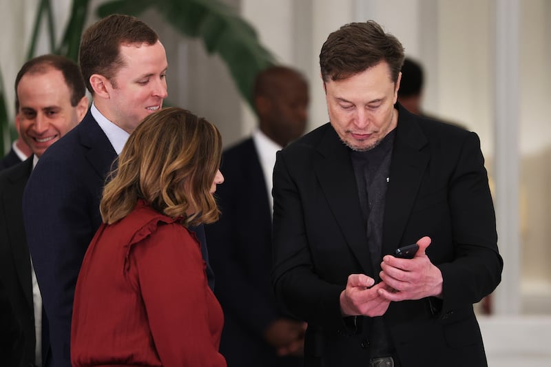 Elon Musk looks at phone.