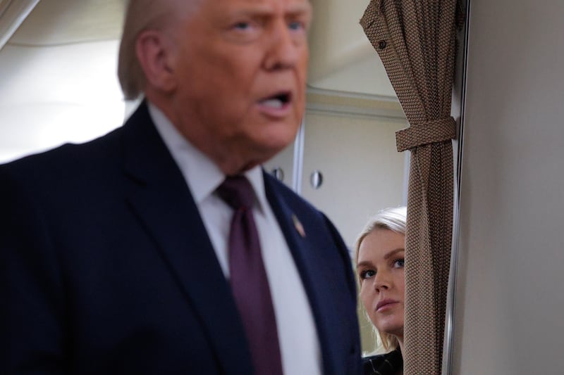 White House Press Secretary Karoline Leavitt listens to U.S. President Donald Trump speak to reporters on board Air Force One.