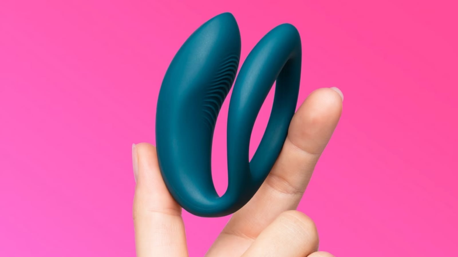 The We-Vibe Sync O sex toy being held up between a person's thumb and pointer finger.