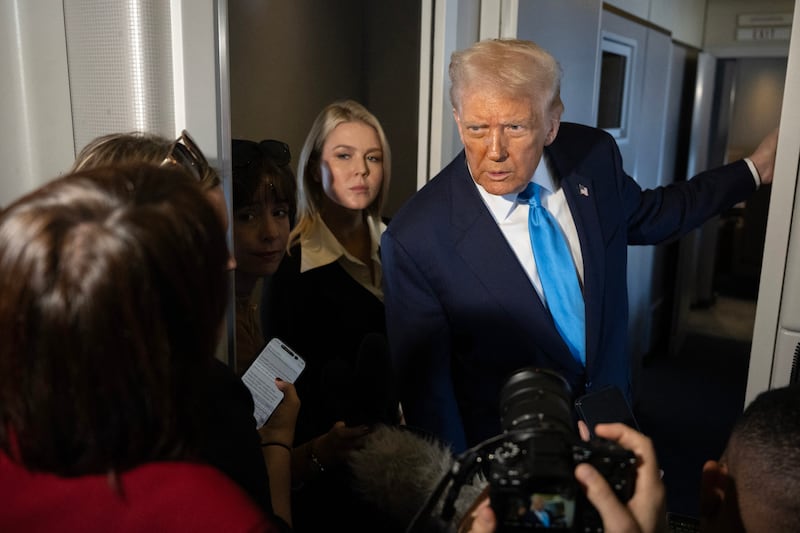 White House Press Secretary Karoline Leavitt watches as President Donald Trump (R) speaks aboard Air Force One while travelling from Japan to South Korea on October 29, 2025.