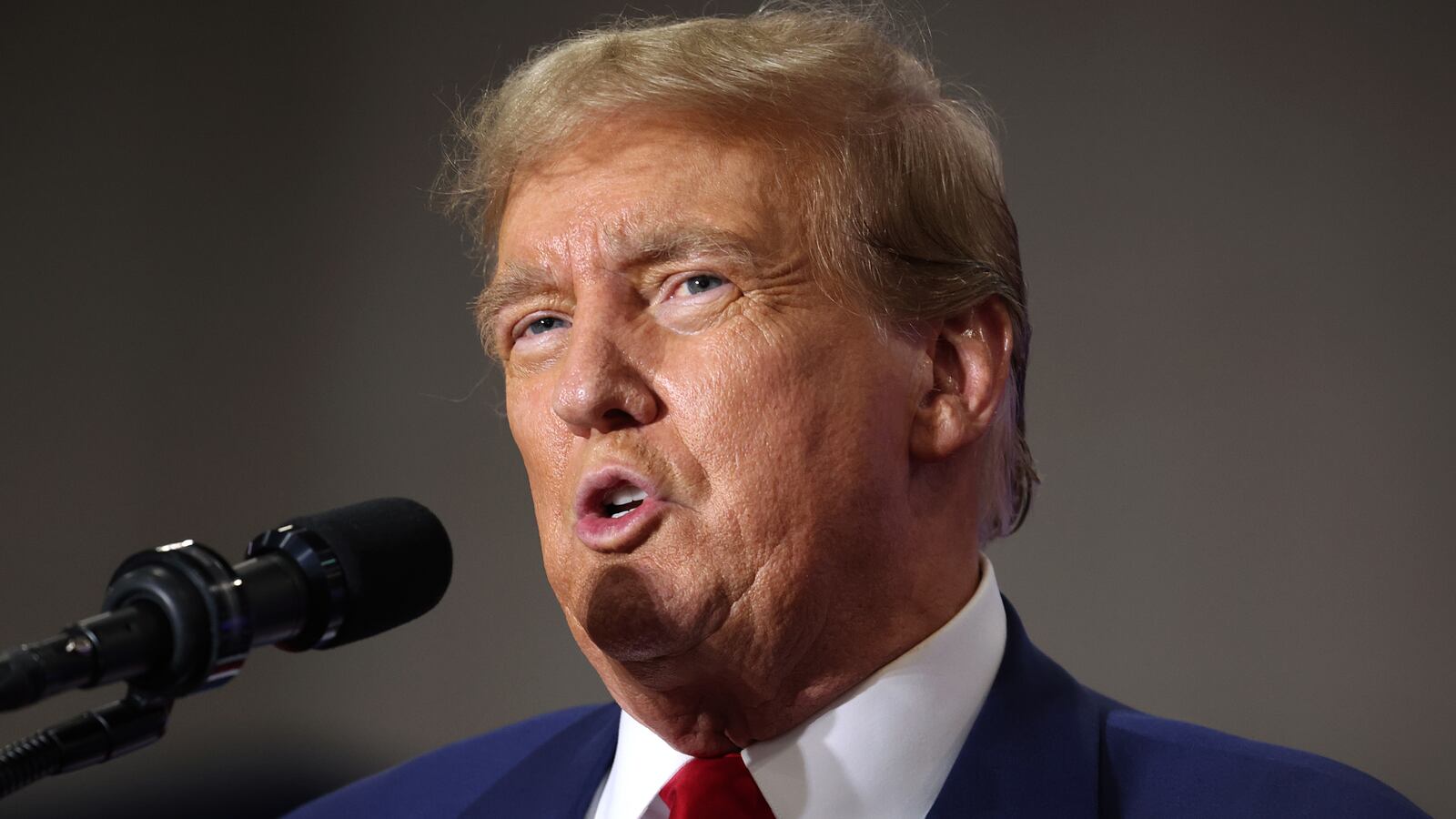 Former President Donald Trump speaks into a microphone.