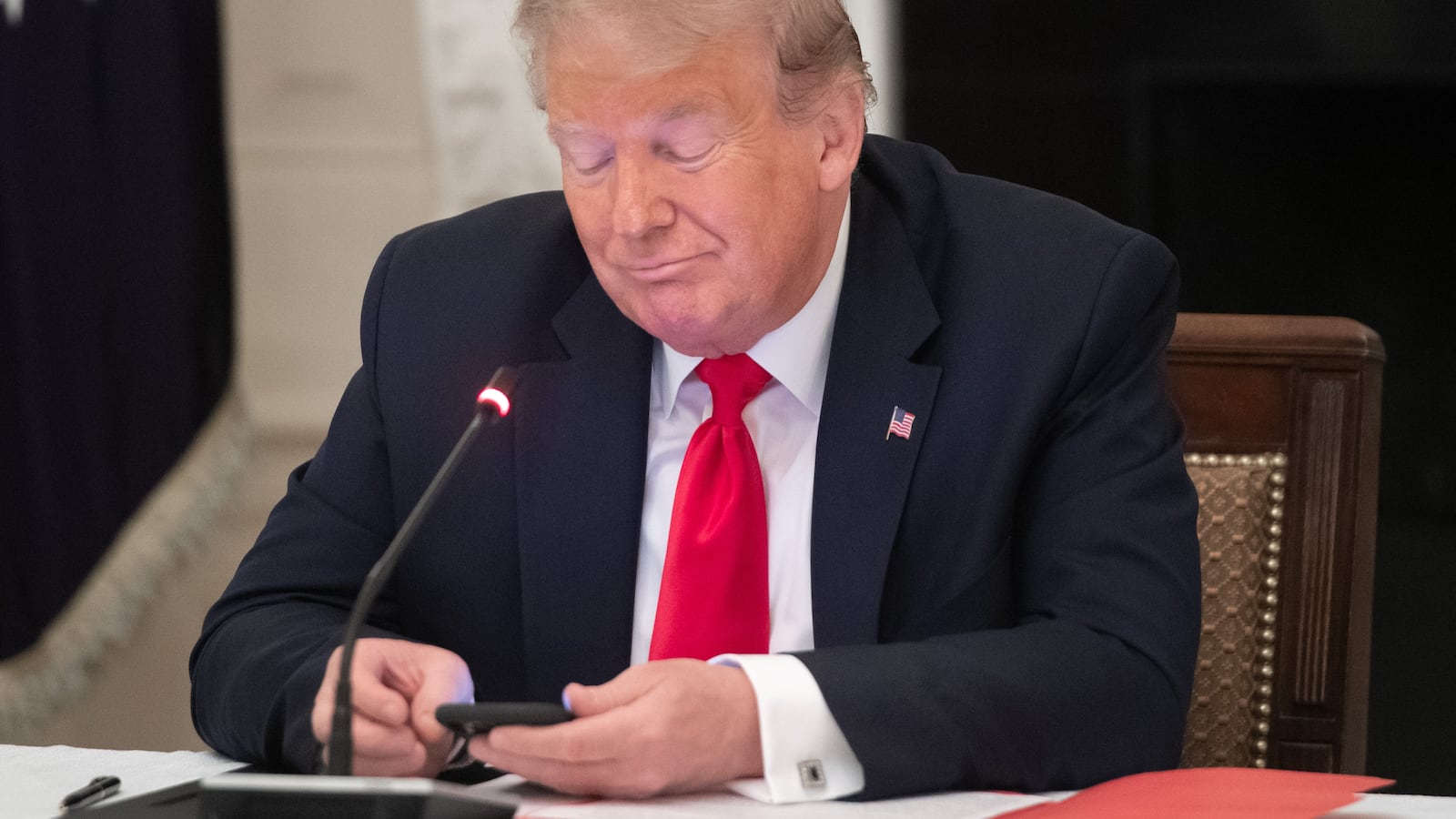 Donald Trump uses his cellphone as he holds a roundtable discussion in the State Dining Room of the White House in Washington, DC, June 18, 2020