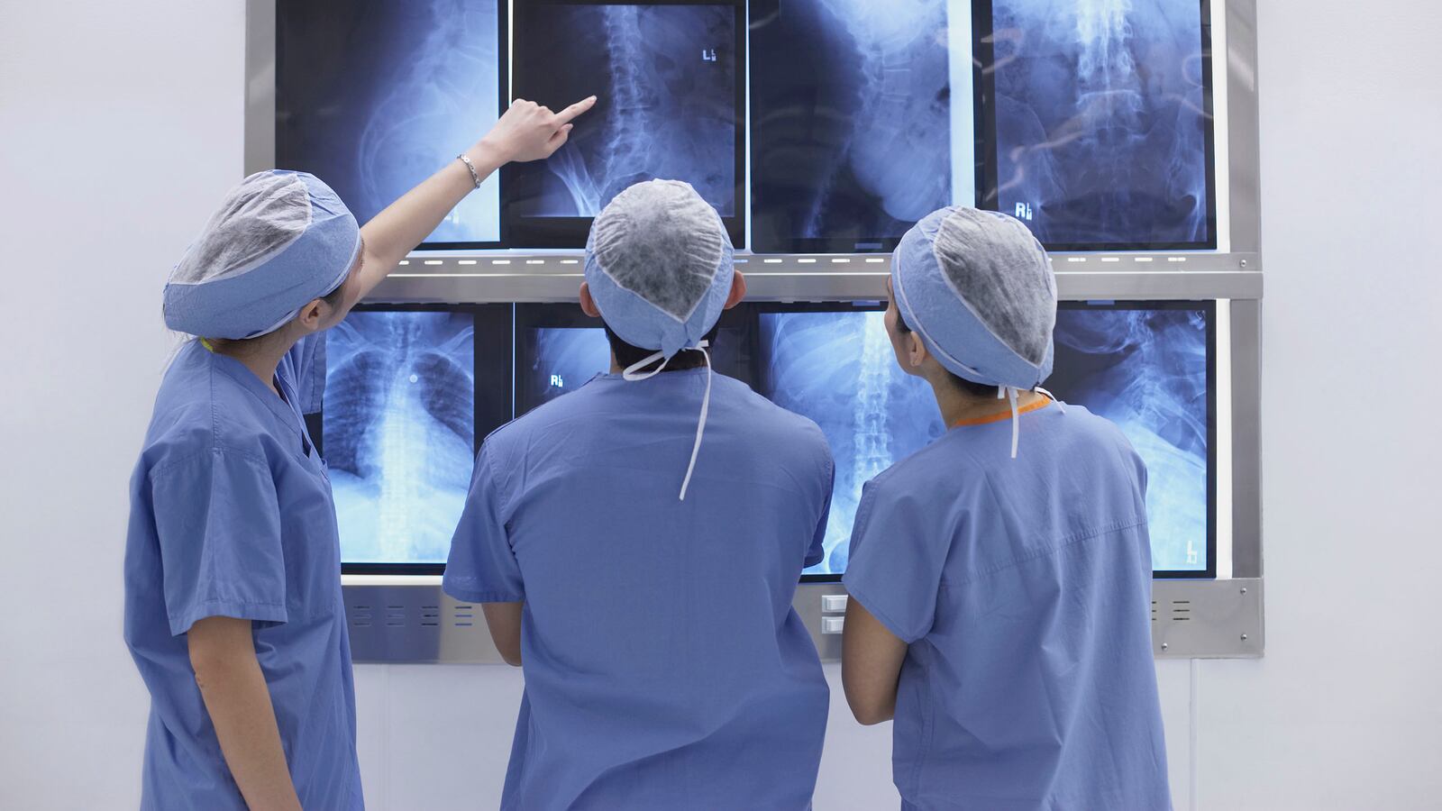 three doctors in scrubs looking at four x-rays acute flaccid myelitis afm cdc centers for disease control rare paralysis polio like mystery