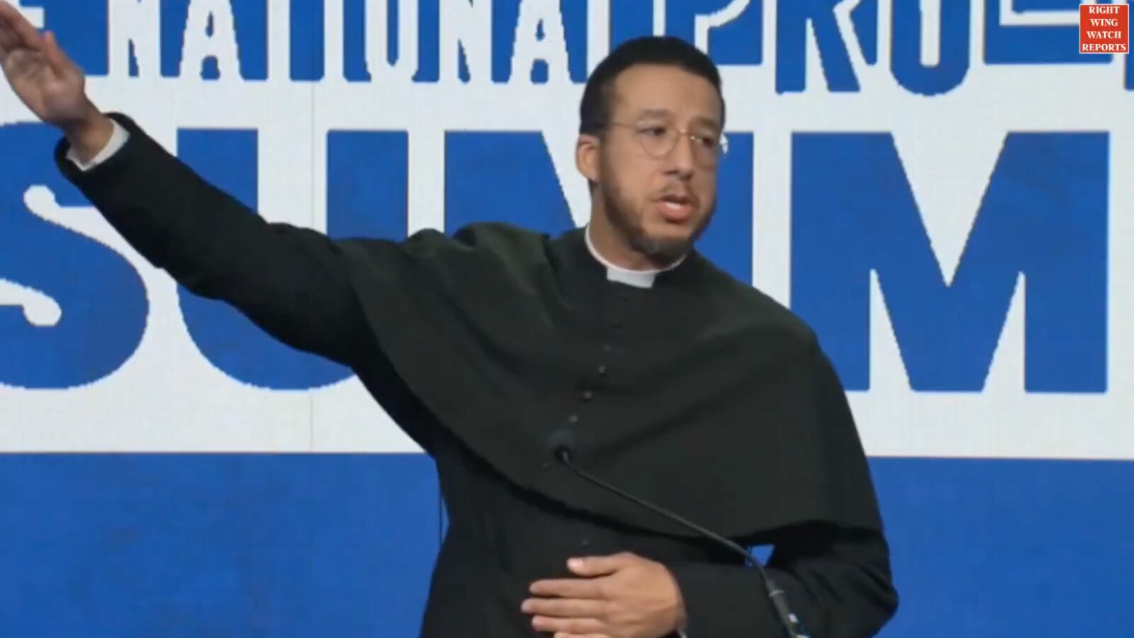 Father Calvin Robinson mimics Elon Musk's Nazi Salute at the National Pro-Life Summit.