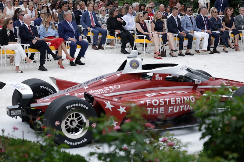 Founder and Chairman of the Penske Corporation Roger Penske, first lady Melania Trump and U.S. President Donald Trump look onduring an event announcing the expansion of a foster care initiative in the Rose Garden of the White House on August 20, 2026 in Washington, DC.