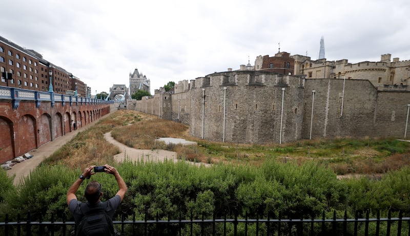A man takes photos of the dry garden outside the Tower of London, turned yellow-brown due to dryness, in London, Britain, on Aug. 18, 2026. In Britain, extreme dryness becomes a defining feature of the summer. Provisional data from the Met Office showed that England and Wales experienced their driest July on record, while nearly three-quarters of England was officially under drought conditions by Aug. 10. (Photo by Li Ying/Xinhua via Getty Images)