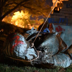 A young boy stands near the statue of Confederate general Albert Pike after it was toppled by protesters at Judiciary Square in Washington, DC on late June 19, 2020. -