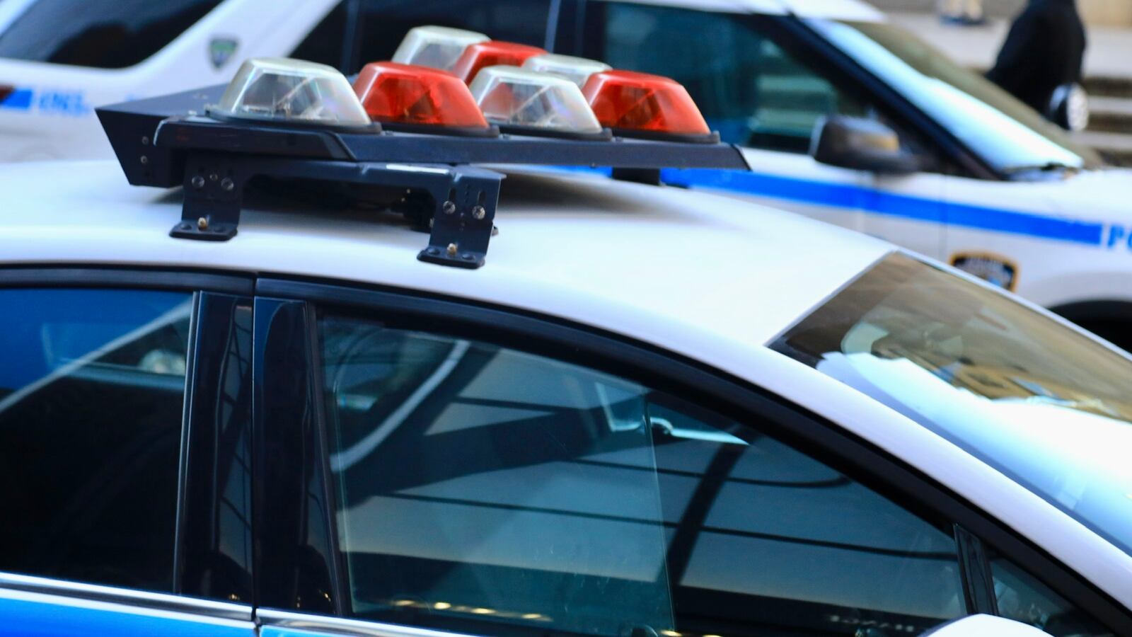 Police vehicles with overhead strobe lights at a crime scene.