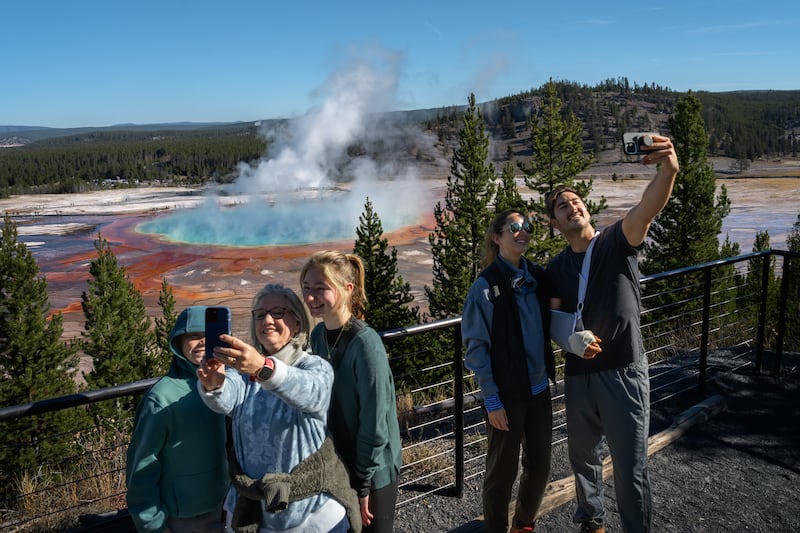 YELLOWSTONE NATIONAL PARK, WYOMING - OCTOBER 09: Tourists take a selfie with the Grand Prismatic Spring on October 9, 2024 in Yellowstone National Park, Wyoming. (Photo by Qian Weizhong/VCG via Getty Images)