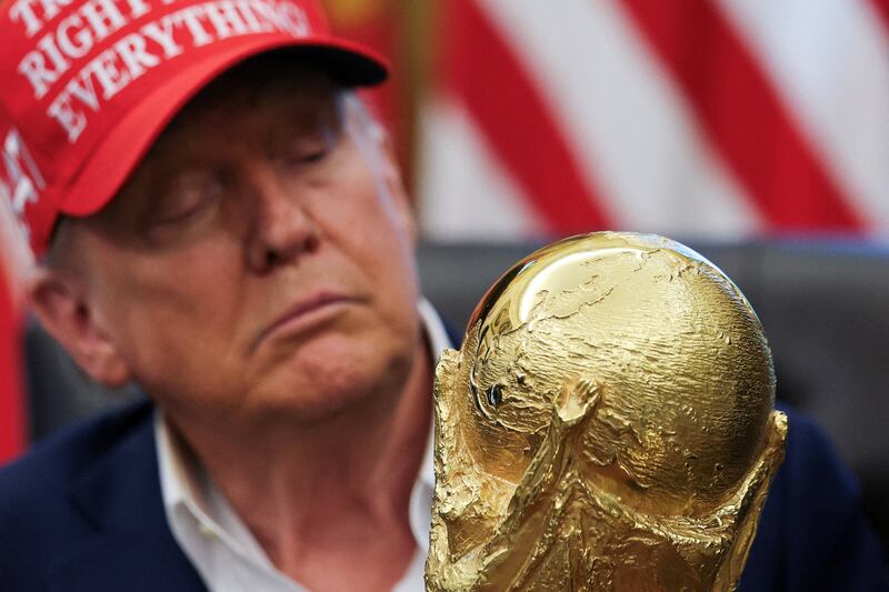 U.S. President Donald Trump holds the FIFA World Cup Trophy, as he makes an announcement on the 2026 FIFA World Cup, in the Oval Office at the White House in Washington, D.C., U.S., August 22, 2025. REUTERS/Jonathan Ernst     TPX IMAGES OF THE DAY