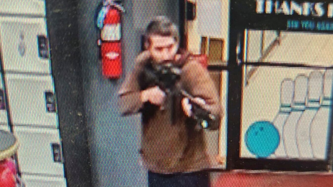 A man identified as a suspect by police points what appears to be a semiautomatic rifle, in Lewiston, Maine.