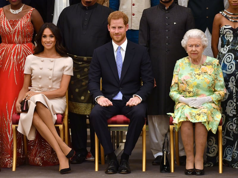 Britain’s Queen Elizabeth, Prince Harry, and Meghan, the Duchess of Sussex, pose for a picture with some of the Queen's Young Leaders at Buckingham Palace in 2018.