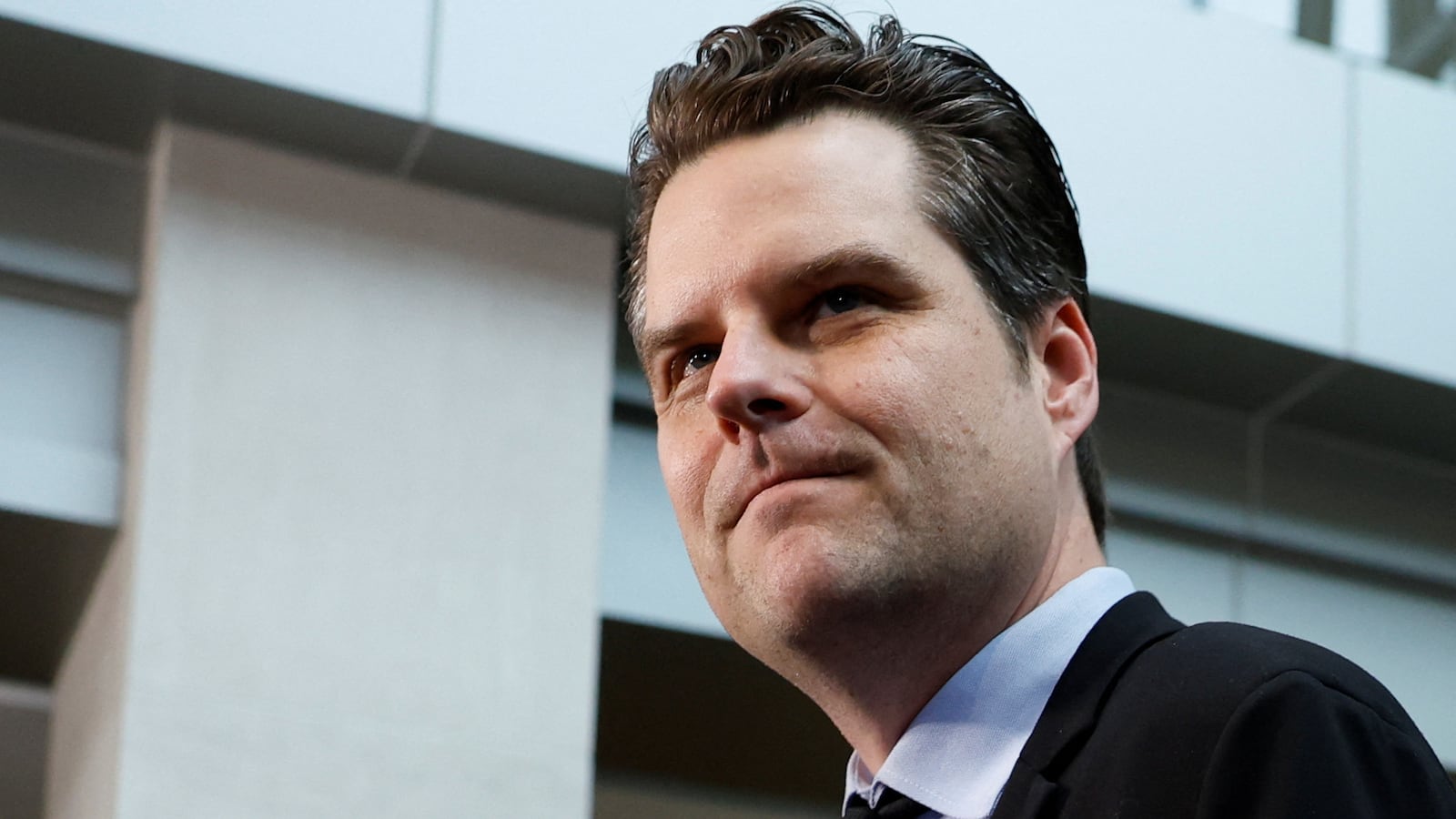 Matt Gaetz, wearing a black suit, looks to his left.