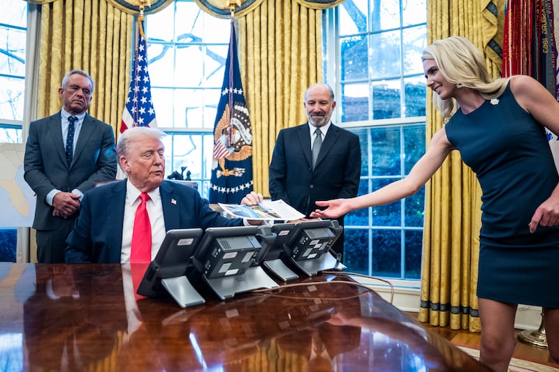 Natalie Harp hands President Donald J Trump a print out as he signs Executive Orders and speaks with reporters in the Oval Office at the White House on Tuesday, Feb 25, 2025 in Washington, DC.